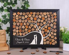 a wedding guest book with a tree and bride and groom silhouette on it, surrounded by leaves