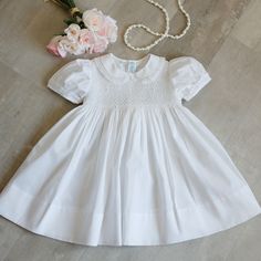 This Traditional Little White Dress Is Super Sweet! A Peter Pan Collar Is Trimmed In A Delicate White French Lace. The Short Puff Sleeves Are Trimmed In A Matching Lace By Faggoted Stitching. The Entire Front Bodice Is Smocked With Alternating Accordion Style Smocking And Lattice Style Smocking. Small White Bullion Roses Are Placed Evenly Throughout. Upper Button Back And A Wide Tie-Back Sash Allows For The Perfect Fit! Timeless, Classy And Heirloom Quality. New With Tags-Perfect Condition. Perf Easter Smocked Dress, Strawberry Print Dress, Sew Ideas, White Baby Dress, Mini Boden Dress, Heirloom Dresses, Dark Green Dress, Little White Dress, Girls Formal Dresses