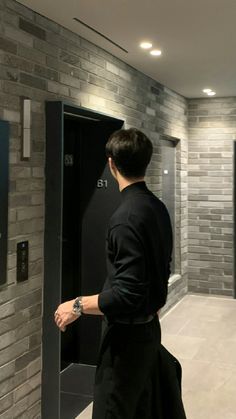 a man standing in front of an elevator with his hand on the door and looking at something