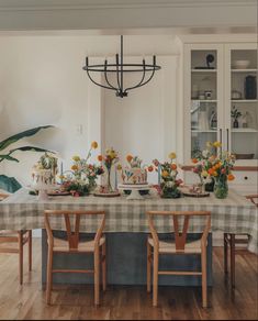 a dining room table with flowers and candles on it, surrounded by chairs in front of the table