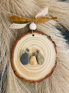 an ornament with rocks and leaves on it sitting on top of a piece of wood