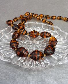 For your consideration I have a lovely vintage translucent amber coloured, glass bead necklace. Similar in colour to tigers eye. Separating these beads are yellow seed beads.  The necklace fastens with a barrel screw clasp. CONDITION In excellent vintage condition! Actual jewellery colour may vary from the images shown. Vintage Orange Beaded Necklace, Vintage Orange Round Beads Necklace, Orange Vintage Necklace With Faceted Beads, Vintage Hand-strung Orange Beaded Necklace, Vintage Amber Glass Necklaces, Amber Color, Glass Bead Necklace, Amber Glass, Amber