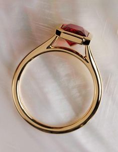 a gold ring with a red stone on it