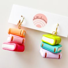 three small books are hanging from hooks on a white surface with a business card in the background