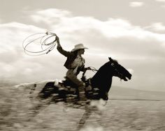 a man riding on the back of a horse while holding a lasso in his hand