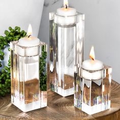 three clear candle holders sitting on top of a wooden table