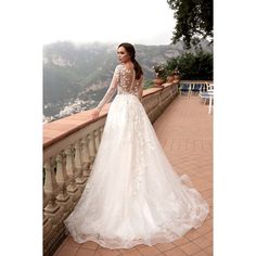 a woman in a wedding dress is standing on a balcony overlooking the water and mountains