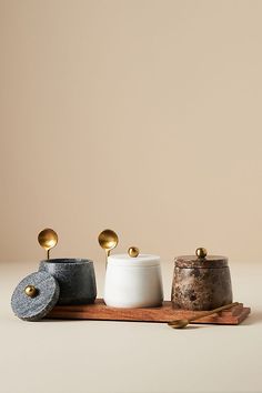 three different types of salt and pepper shakers on a cutting board with spoons