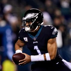 a man holding a football in his right hand and wearing a helmet on the other