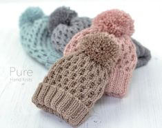 three knitted hats with pom - poms on them