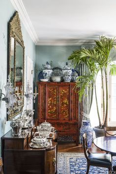 a living room filled with furniture and a potted plant in front of a mirror