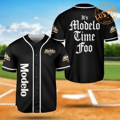 a black baseball jersey with the words model time too on it and an image of a baseball field in the background