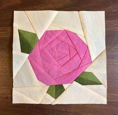 a piece of paper with a pink rose on it sitting on top of a wooden table