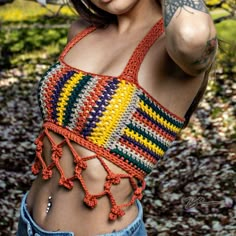 a woman wearing a colorful crochet top and jeans