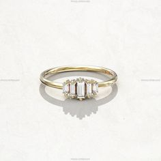 three stone ring on white background with shadow from the top left hand side, in yellow gold