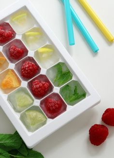 some fruit and ice cubes on a white tray with blue strawberries, raspberries