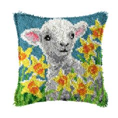 a pillow with an image of a sheep in the grass and flowers on it's side