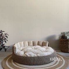 a round dog bed sitting on top of a rug next to a potted plant