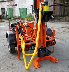 an orange and black machine with yellow hoses attached to it's back end