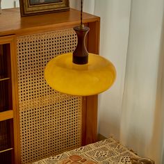 a yellow lamp hanging from the ceiling next to a table with a basket on it