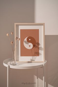 a white table with a vase filled with flowers and a painting on the wall behind it