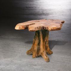 a tree stump table sitting on top of a cement floor