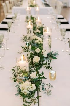 a long table with white flowers and candles on it is set up for a formal dinner