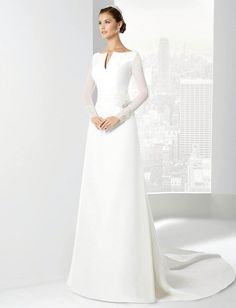 a woman in a white wedding dress standing next to a window with the city skyline behind her