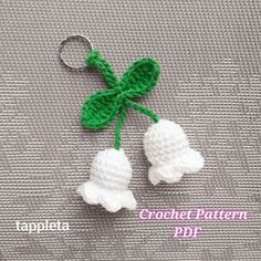 two crocheted white flowers are attached to a keychain with a green leaf