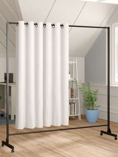 a white curtain hanging on top of a metal frame in front of a wooden floor