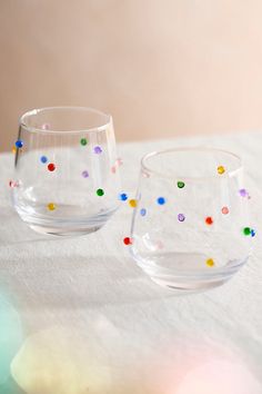 two glasses sitting on top of a table covered in confetti and colored dots