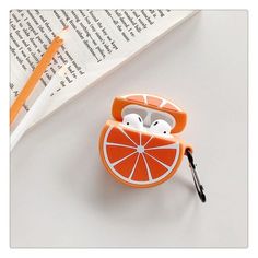 an orange slice shaped airpods case sitting on top of a book