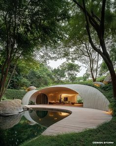 an outdoor swimming pool surrounded by trees and grass with a circular shaped building in the background