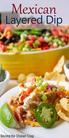 mexican layered dip with tortilla chips and green peppers on the plate next to it