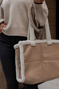 Beige vegan leather handbag. Held by an ivory sherpa trim. This item is Final Sale. Cream Rectangular Shoulder Bag For Winter, Winter Cream Rectangular Shoulder Bag, Cream Winter Shoulder Bag, Everyday Rectangular Shoulder Bag With Plush Lining, Cream Tote Shoulder Bag For Winter, Winter Cream Tote Shoulder Bag, Everyday Tote Bag With Plush Lining, Winter Cream Shoulder Bag For Daily Use, Cream Shoulder Bag For Winter Travel