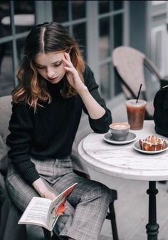 a woman sitting at a table reading a book