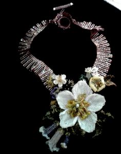 This a larger style necklace that is really striking yet casual. The focal point is a large white blossom made with seed beads, surrounded by beaded leaves and other types of flowers. I want to say the necklace portion and the flowers that are hanging down are a little more purple than they appear in the photos. White Bohemian Necklace With Flower Pendant, White Bohemian Necklace With Flower Charm, Bohemian White Necklace With Flower Charm, White Bohemian Jewelry With Flower Decoration, White Bohemian Flower Charm Necklace, Bohemian White Jewelry With Flower Decoration, Bohemian White Flower Charm Necklace, White Bohemian Flower Necklace, White Beaded Flower Pendant Necklace