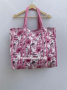 a pink and white bag hanging on a wooden hanger