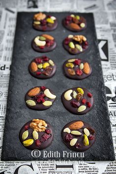 chocolate covered cookies with nuts and dried cranberries on a baking sheet, ready to be eaten