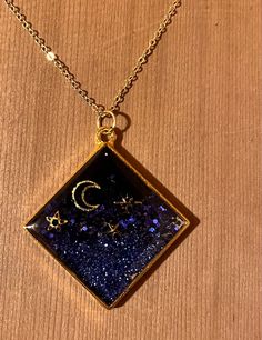 a square necklace with the moon and stars on it