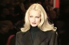 a woman with blonde hair is walking down the runway wearing a black jacket and pants