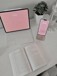 an open laptop computer sitting on top of a desk next to a phone and book