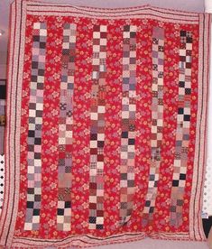 a large red quilt hanging on the wall