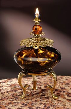 a glass candle holder on top of a table with a lit candle in the middle