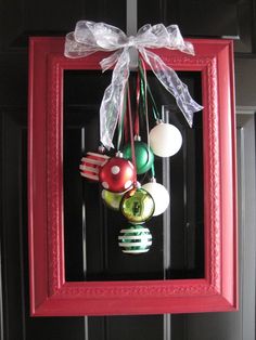 a red frame with ornaments hanging from it's sides and a bow on top