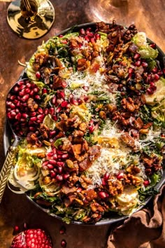 a pan filled with meat and vegetables on top of a wooden table next to pomegranates