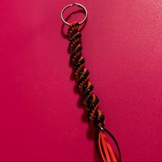 a red and black keychain on a pink surface