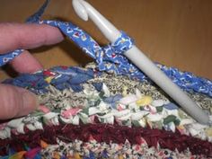 someone is crocheting the edge of a piece of fabric with a white handled crochet hook