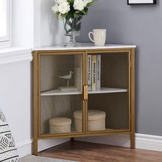 a glass cabinet with some books and flowers in it next to a vase filled with white roses