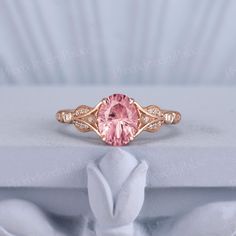 a pink diamond ring sitting on top of a white cloth